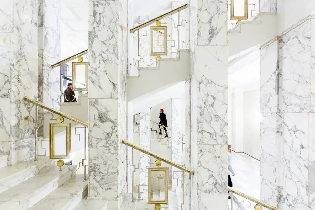 Three people walking in the stairways of the Parliament Building in Helsinki, Finland